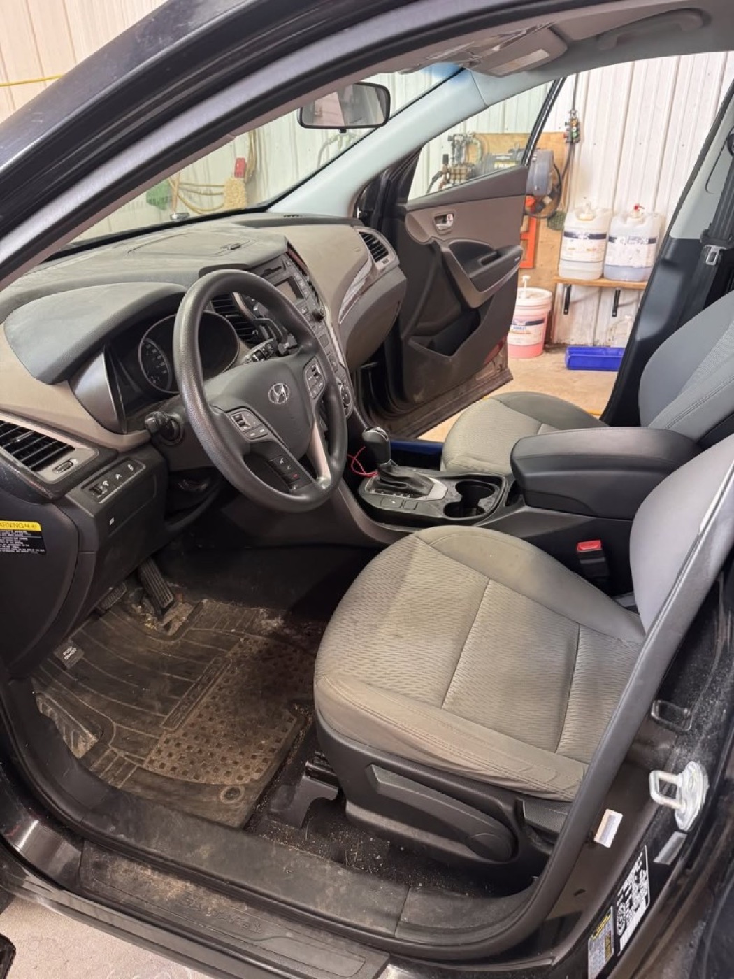 Vehicle interior before mobile detailing — dusty dashboard, dirty floor mats, and worn seats