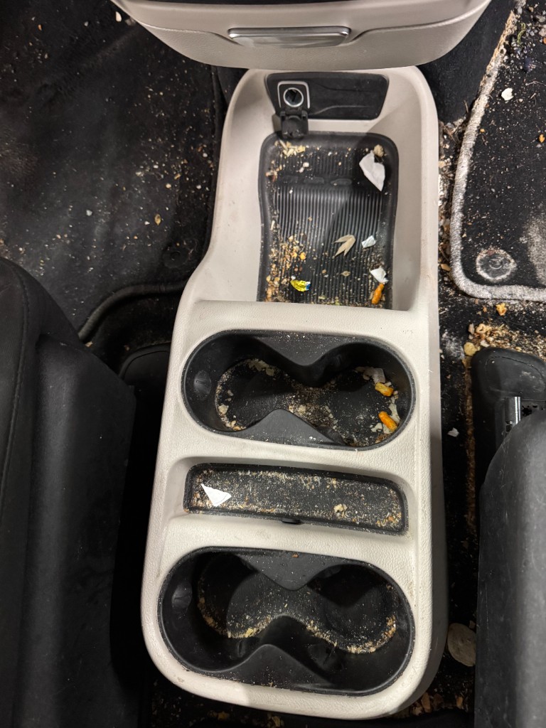 Center console and cup holders filled with crumbs and debris before interior detailing